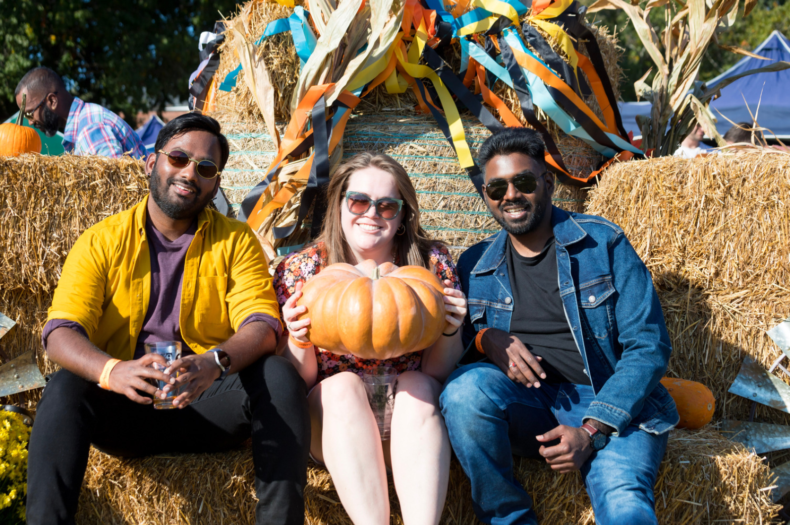 Three people with a large pumpkin pose at Falling for Local 2022