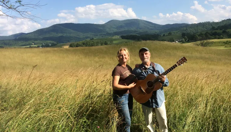 man and woman in field with guitar