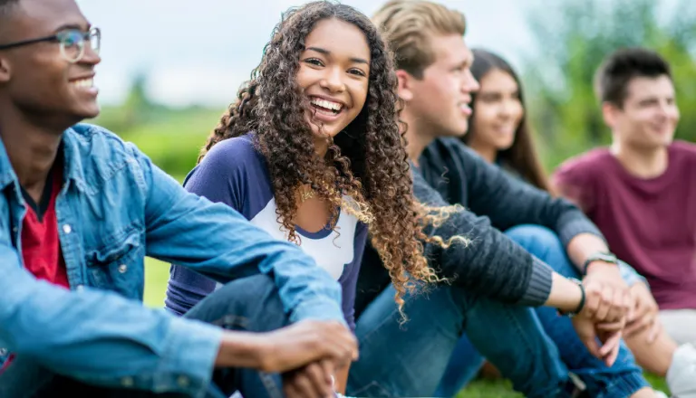 Teens sitting outside in a group stock image