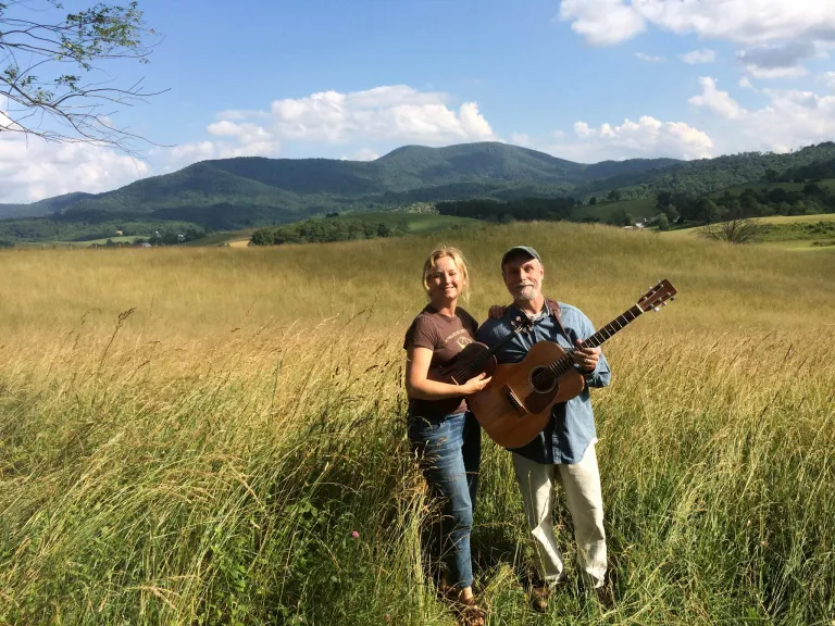 man and woman in field with guitar