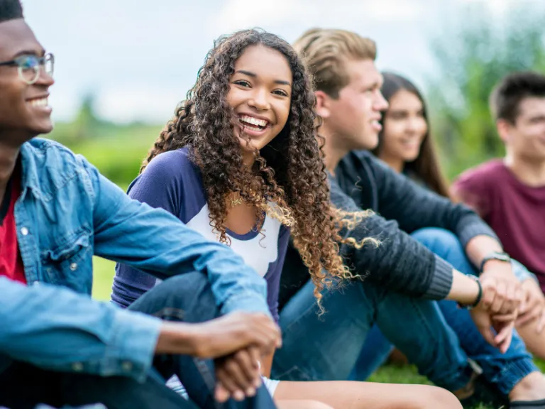Teens sitting outside in a group stock image